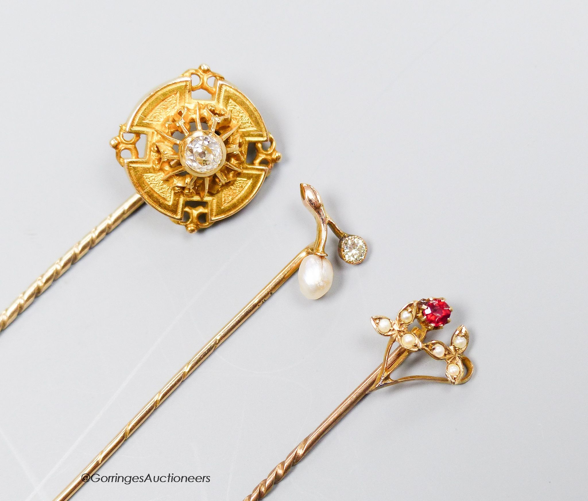A Victorian diamond set gold target stickpin, another with pearl and diamond and a third with red stone and pearls.
